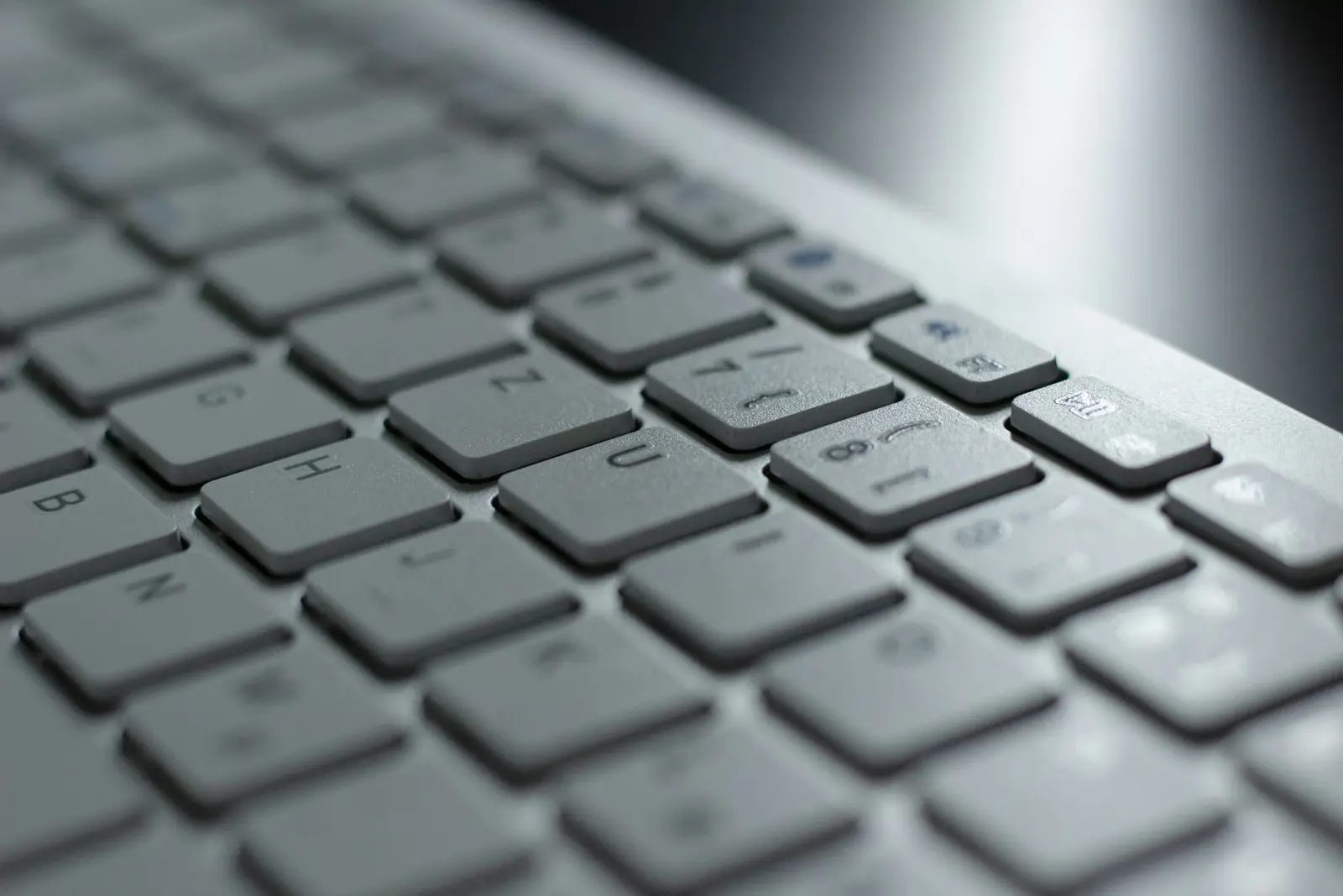 A close-up of a pale grey computer keyboard seen at an angle