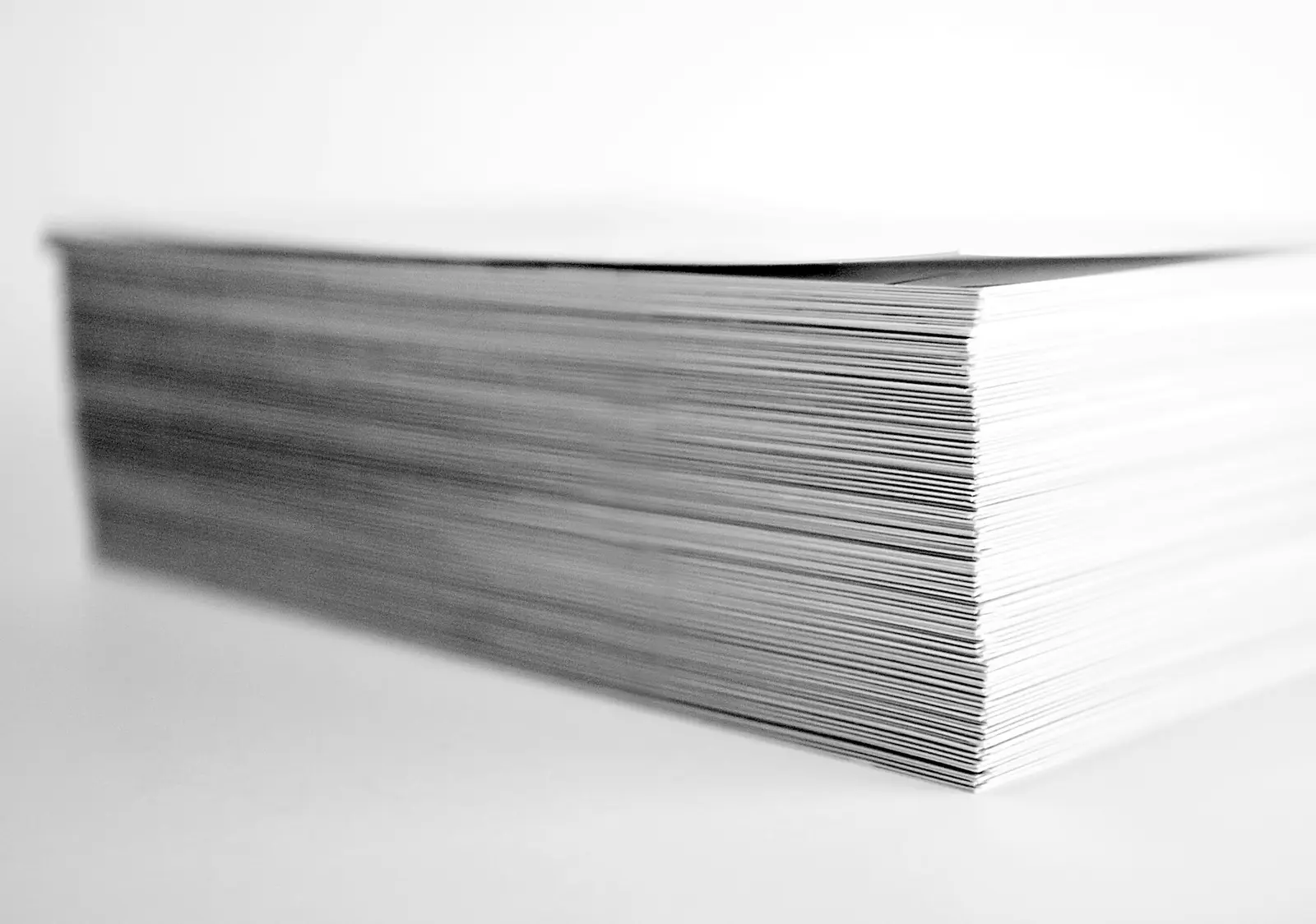 A thick stack of white paper seen from the side in close-up, edges in sharp focus