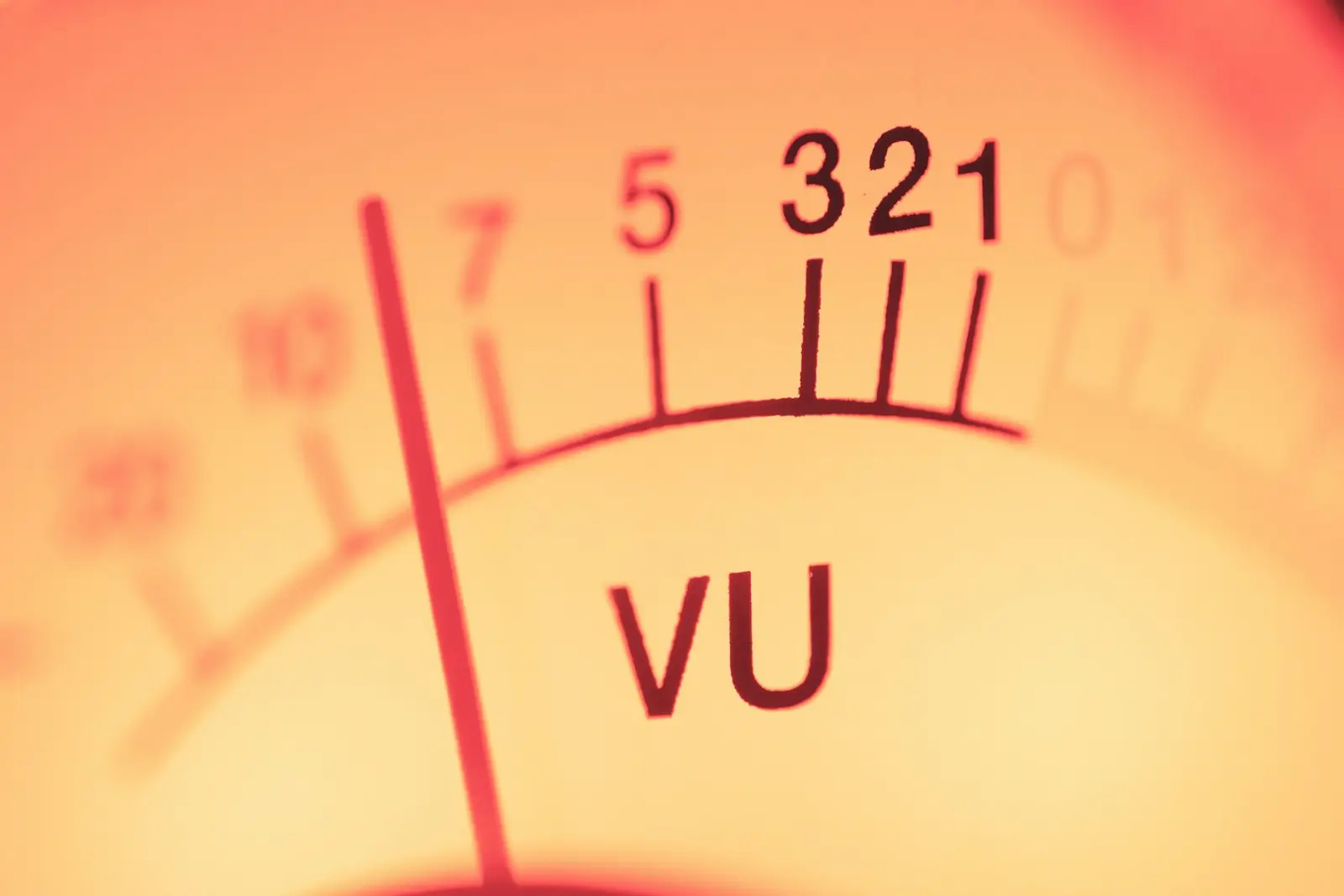 Close-up of an analog VU meter with its red needle near the left of a scale marked 7, 5, 3, 2, 1