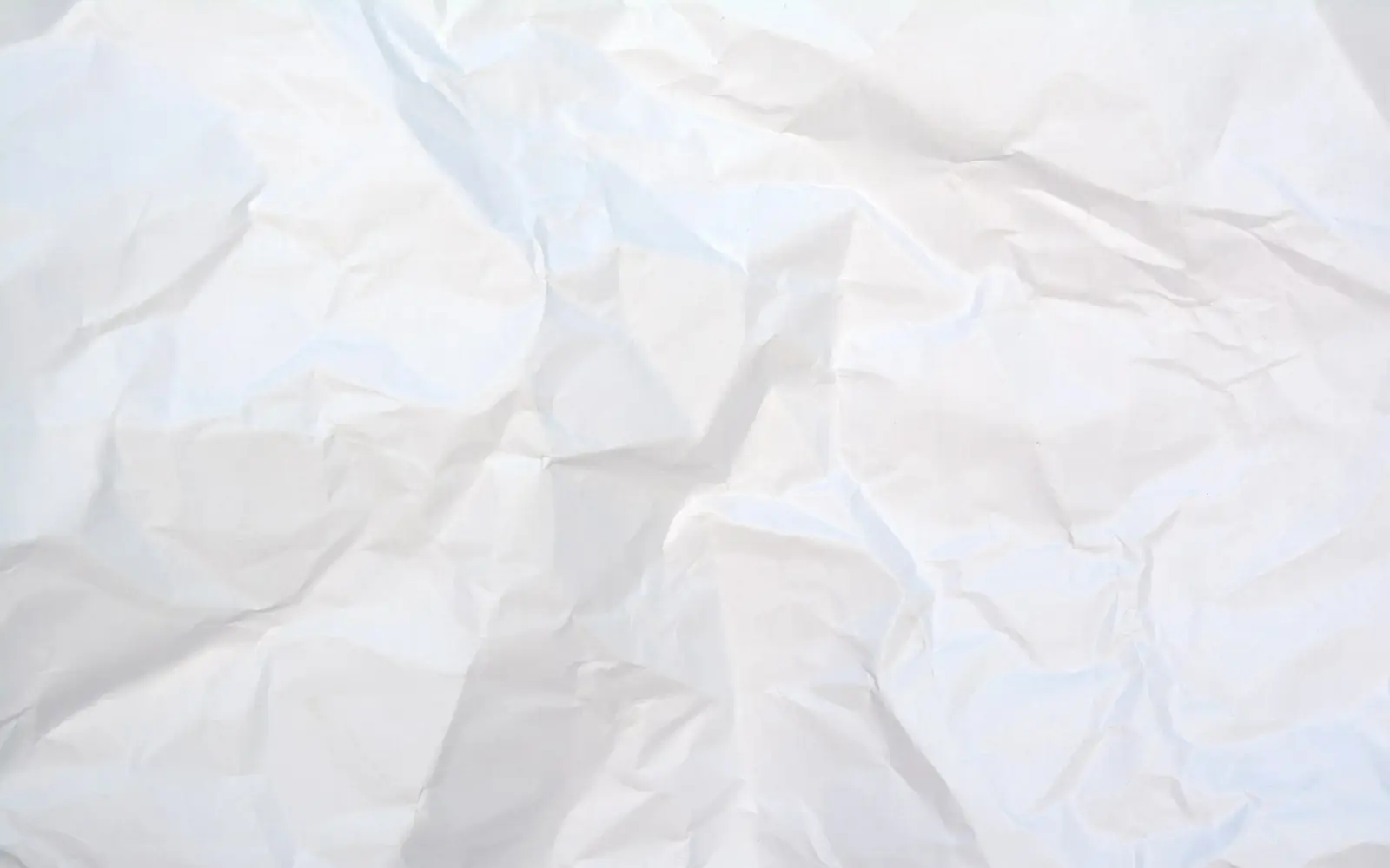 A sheet of white paper covered in deep creases and folds, filling the frame